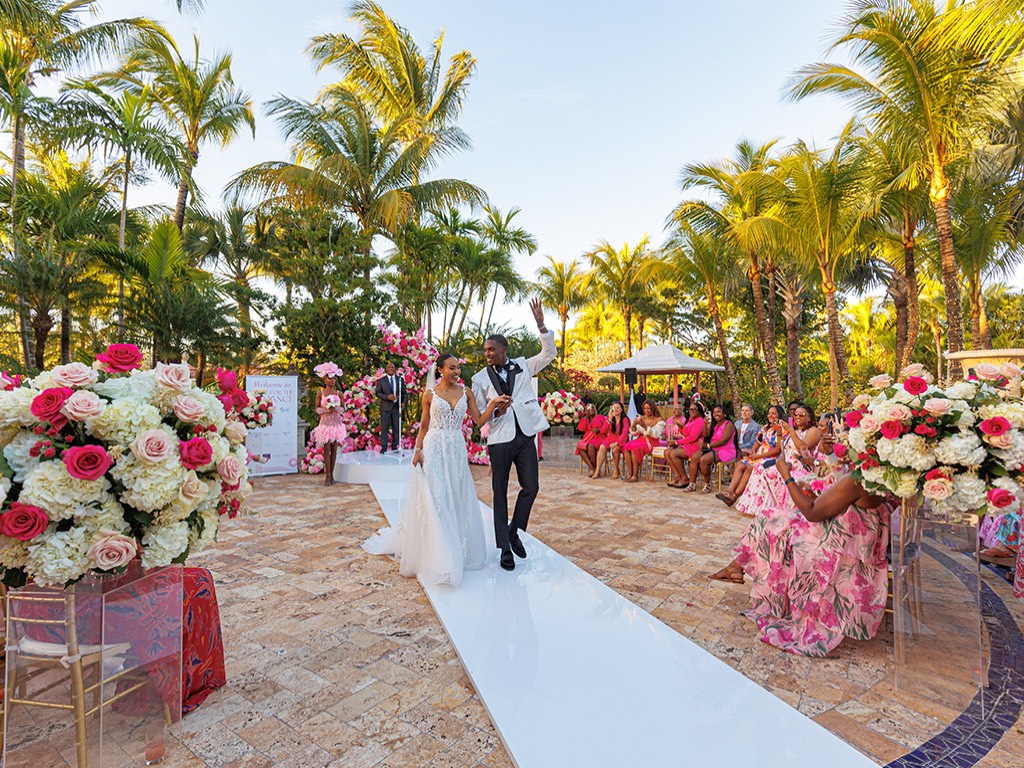 Una ceremonia en jardín enmarcada por palmeras.